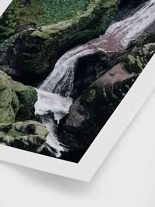 Vandfald mellem mosdækkede klipper på indrammet naturplakat