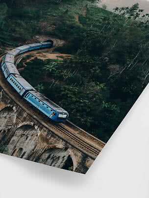 Blue train on a curved stone viaduct through lush forest toward a tunnel