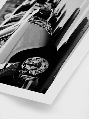 Black-and-white print showing a close-up of a classic sports car and other cars