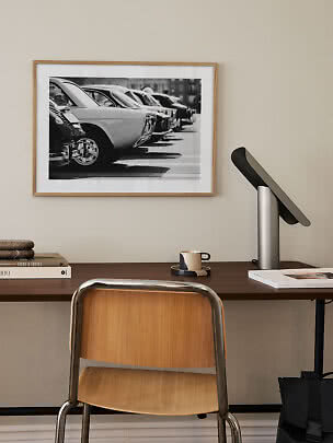 Framed black-and-white photo of parked vintage cars above a desk
