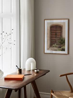 Foto enmarcada de una puerta rústica de madera en pared beige sobre mesa de madera oscura
