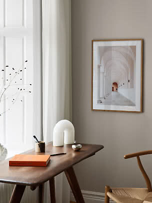 Framed photo print of an arched colonnade on a beige wall above a wooden desk
