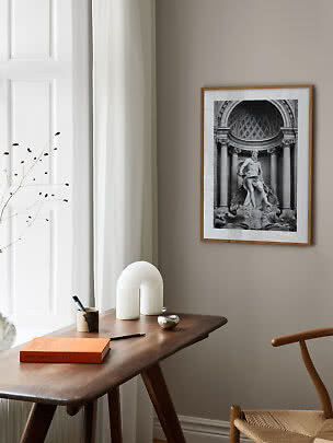 Affiche d’art noir et blanc encadrée d’une statue classique au-dessus d’un bureau en bois