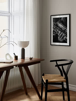 Foto incorniciata in bianco e nero di un saxofono sopra una scrivania in legno e sedia nera