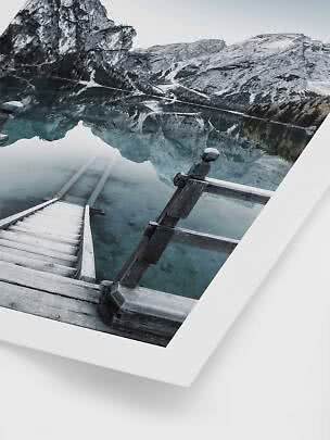 Photo of wooden steps into a clear mountain lake with snowy peaks reflected in the water
