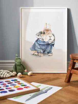 Framed rabbit print with a watercolor bunny in a blue coat, leaning against the wall in a kids room