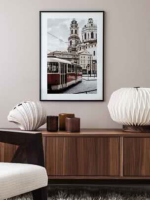 Poster incorniciato con tram davanti a torri di chiesa sopra una credenza in legno
