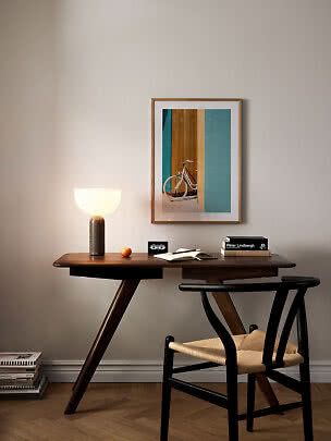 Bureau en bois foncé avec lampe allumée, chaise et affiche de vélo encadrée au mur