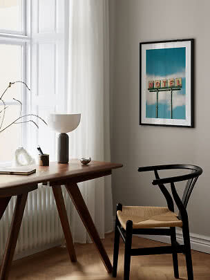 Indrammet plakat med motelskilt på blå himmel hænger over skrivebord og sort stol
