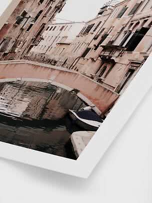 Foto enmarcada de un canal con pequeño puente, barco y edificios en tonos pastel