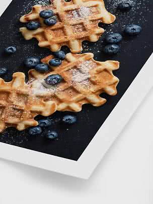Waffle dorate con mirtilli e zucchero a velo su vassoio nero