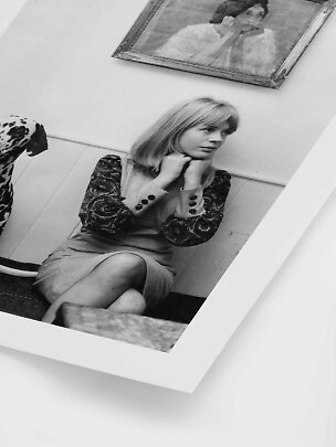 Foto en blanco y negro de una mujer rubia sentada, un dálmata y un retrato enmarcado en la pared