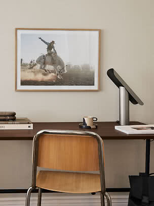 Photo de rodéo encadrée au-dessus d’un bureau avec chaise, lampe, livres et tasse