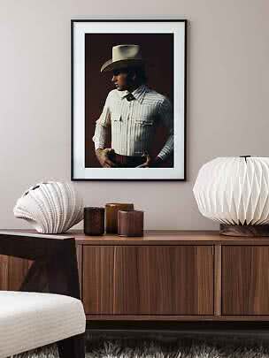 Affiche encadrée d’un homme en chapeau cowboy et chemise rayée au-dessus d’un buffet en bois