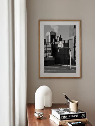 Framed black-and-white photo of a basketball hoop on an urban court above a wooden table