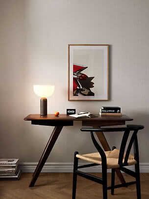 Wooden desk with black chair, glowing table lamp, books, and framed car photo on the wall