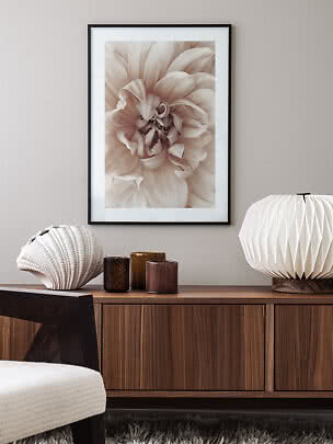 Affiche florale beige encadrée au-dessus d’un buffet en bois avec lampe sculpturale et vases