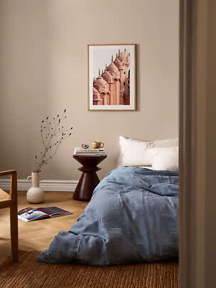 Affiche encadrée de dômes roses au-dessus d’un lit dans une chambre beige