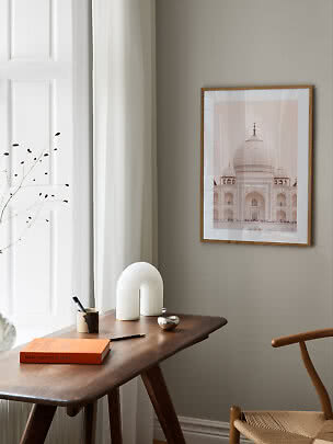 Lámina enmarcada del Taj Mahal en pared beige sobre escritorio de madera junto a una ventana