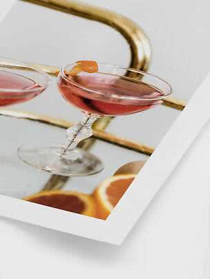 Bicchiere da cocktail con drink rosa e scorza d’arancia su vassoio a specchio