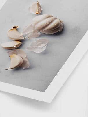 Spicchi d’aglio e una testa d’aglio intera su una superficie di marmo grigio chiaro