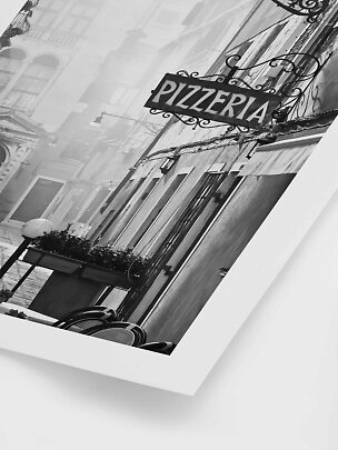 Black-and-white photo of a narrow street with a pizzeria sign on a building