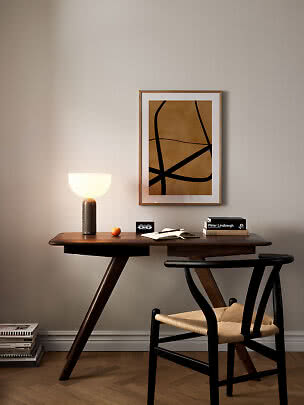 Holzschreibtisch mit leuchtender Tischlampe, Stuhl, Büchern und abstraktem Wandbild