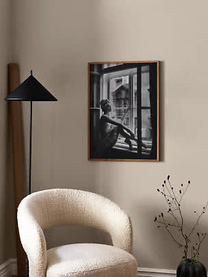 Affiche encadrée en noir et blanc d’une ballerine à la fenêtre au-dessus d’un fauteuil crème