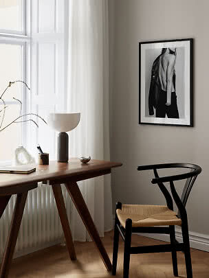 Chaise noire en bois avec assise tressée près d’un bureau dans une pièce lumineuse