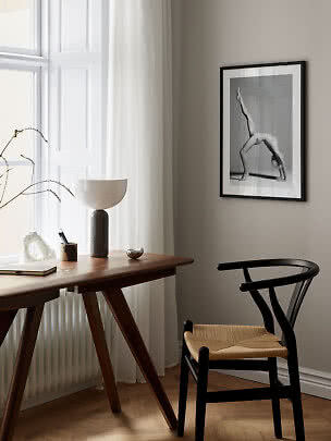 Espace de travail minimaliste avec bureau en bois, chaise noire, lampe et photo noir et blanc encadrée