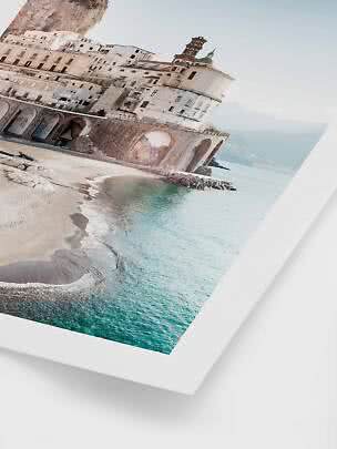 Angled photo of a coastal town with beach, arches and church dome by turquoise sea