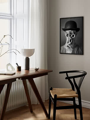 Minimalist home office with wooden desk, black chair and black-and-white wall poster