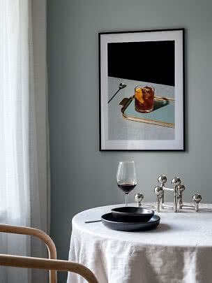 Gerahmter Kunstdruck mit Drink auf Tablett über gedecktem Tisch mit Weinglas und schwarzen Tellern