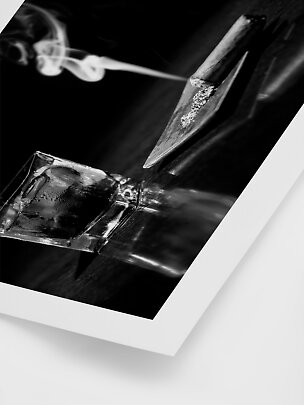 Foto in bianco e nero di uno spinello fumante, vassoio per rollare e bicchiere con ghiaccio.