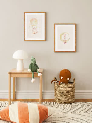 Cozy kids' room with two framed animal prints, table lamp, plush toy on stool, and basket with octopus.