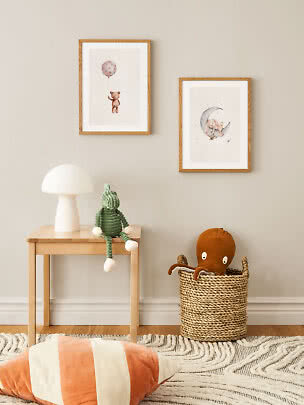 Kids room with two framed animal prints, table lamp, green plush toy on wooden table and basket