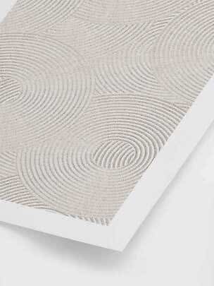 Close-up of a beige rug with wavy concentric patterns and a white border