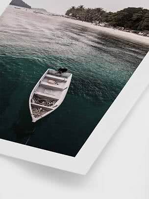 Small white boat moored in clear water near a palm-lined sandy beach