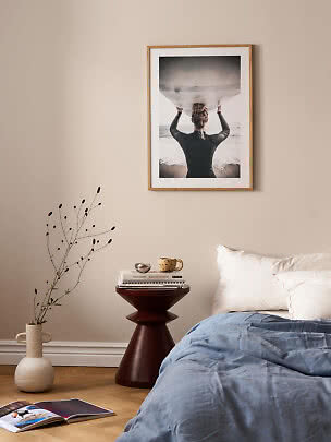 Chambre avec couette bleue et photo de plage encadrée sur mur beige