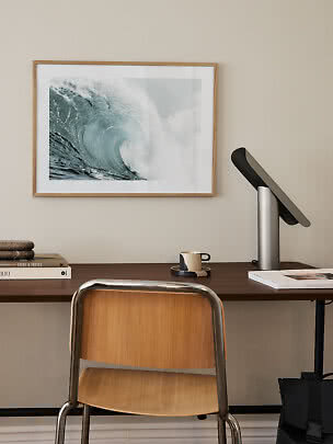 Desk with chair, lamp and framed ocean wave print on the wall