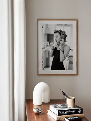 Framed black-and-white photo of woman on phone above wooden table with books and decor