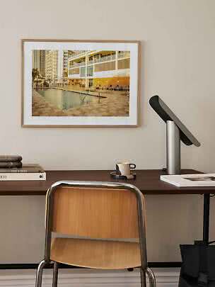 Framed photo of a pool area by a modern apartment building above a desk