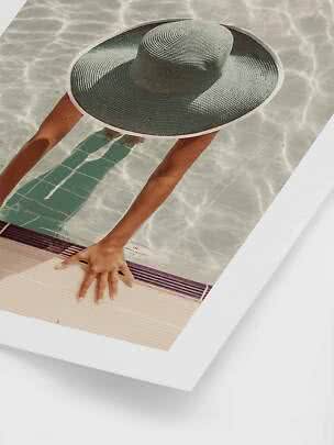 Dark green woven wide-brim sun hat shown on a photo by a swimming pool