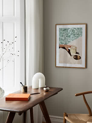 Gerahmtes Bild an der Wand über einem Holztisch in einem hellen, modernen Raum