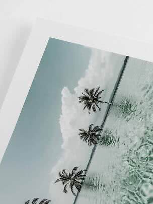 Framed photo of a tropical beach with palm trees, calm sea and clouds