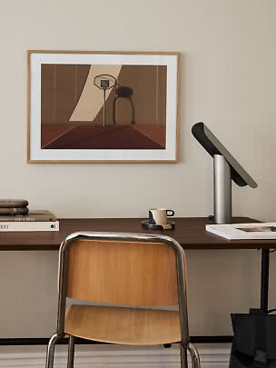 Schreibtisch mit Holzstuhl, moderner Tischlampe und gerahmtem Basketballbild an der Wand