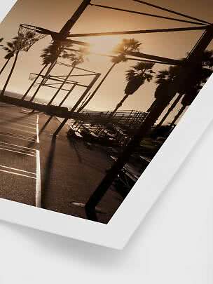 Beachside basketball courts at sunset with palm trees and empty bleachers