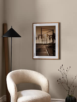 Framed poster of a basketball court with palm trees at sunset on a beige wall