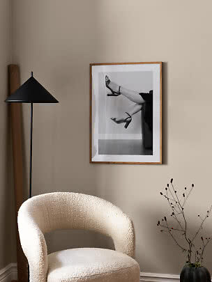 Living room corner with cream armchair, black floor lamp and framed black-and-white print on beige wall