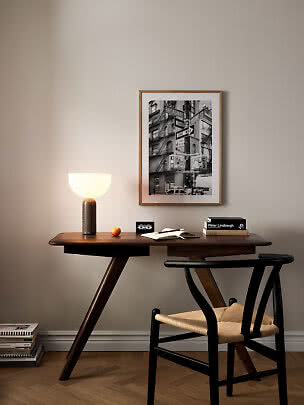 Dark wood desk with chair, lit table lamp, and framed black-and-white city photo on the wall